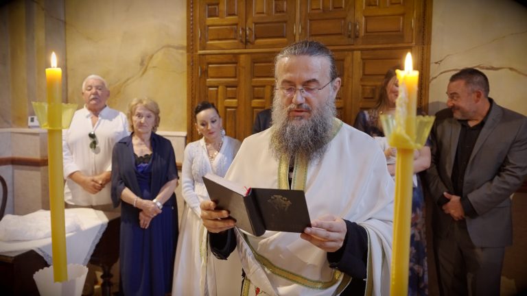 Sveštenik čita molitvu uz upaljene sveće na krštenju